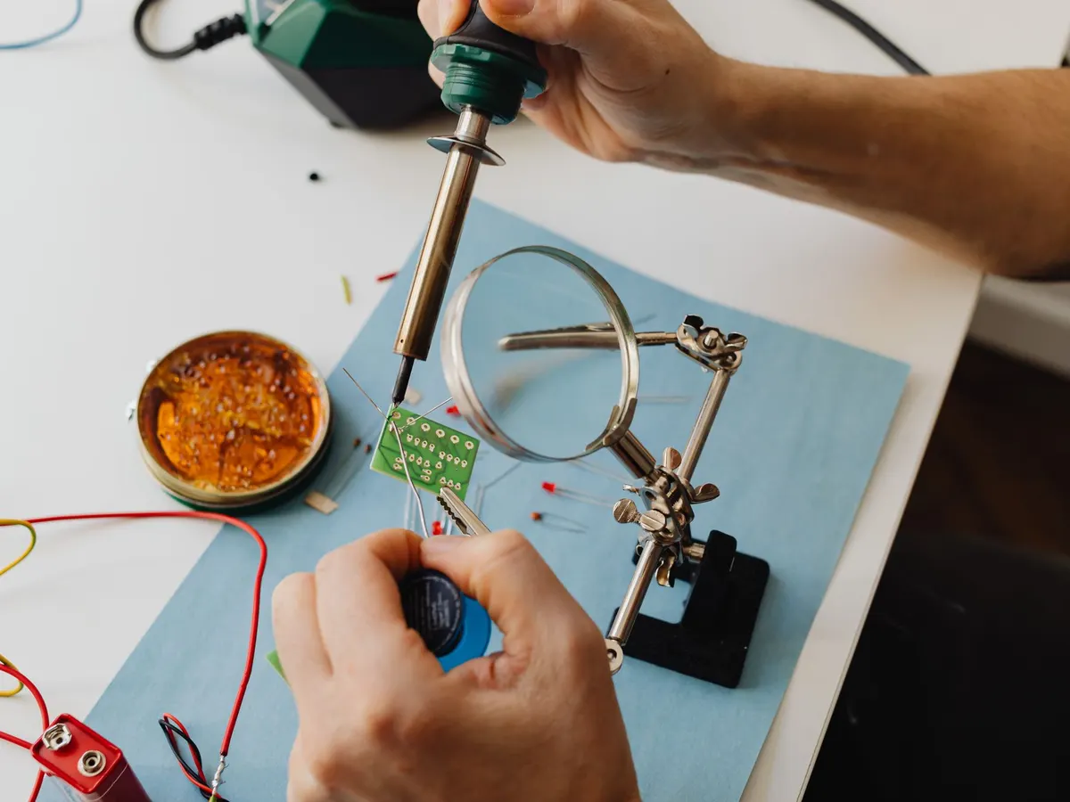 Técnico reparando una placa con lupa y soldador